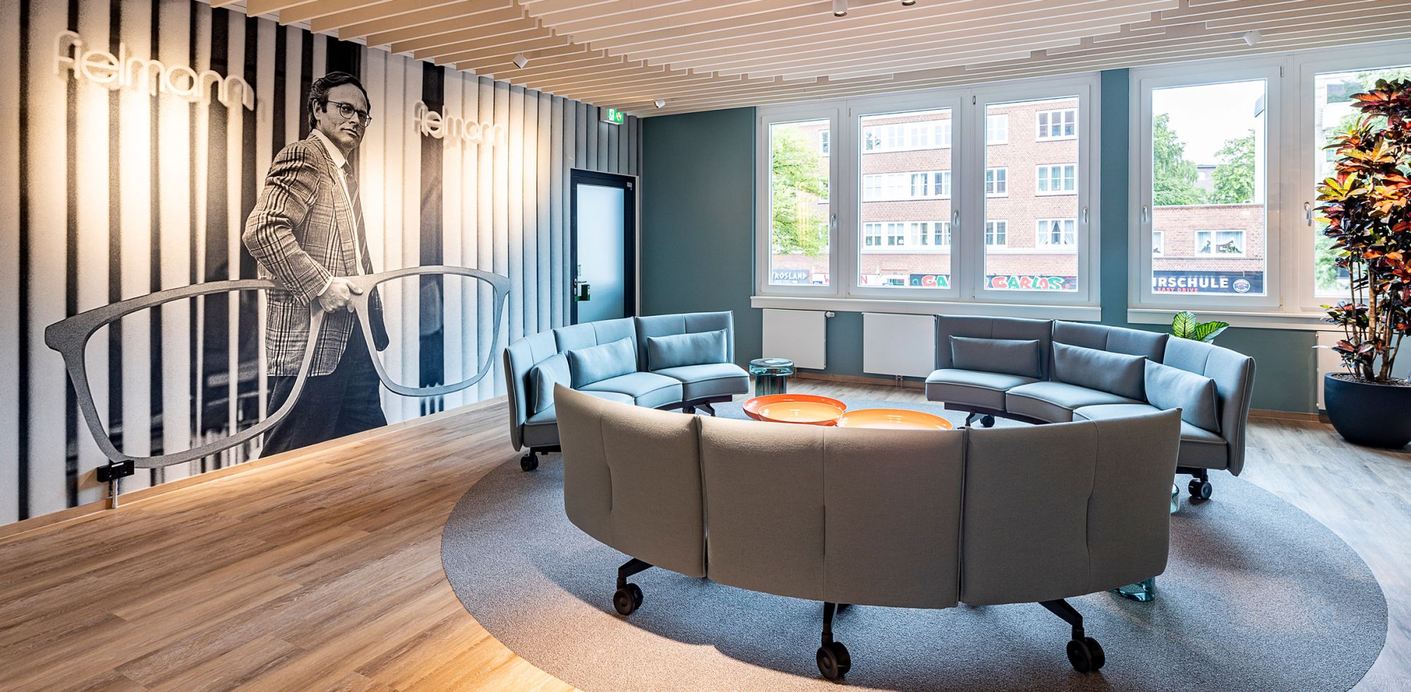 Moderner Loungebereich mit rundem Sofa und Wandportr&auml;t.