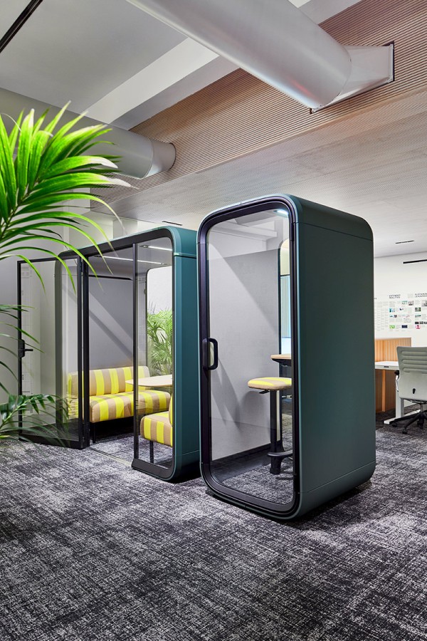 Showroomfoto schalldichte Boxen: Framery Four Besprechungsbox mit 2 gelben Sofas und Framery One Telefonbox für eine Person