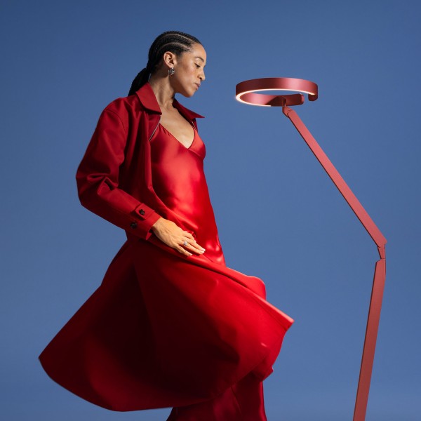 Occhio Gioia Letture Stehleuchte in der Farbe rosso intenso neben Frau.