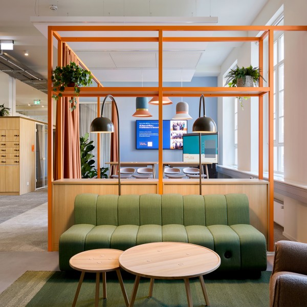 Moderner Loungebereich bei 4flow Berlin mit grünem Sofa und Holzmöbeln.