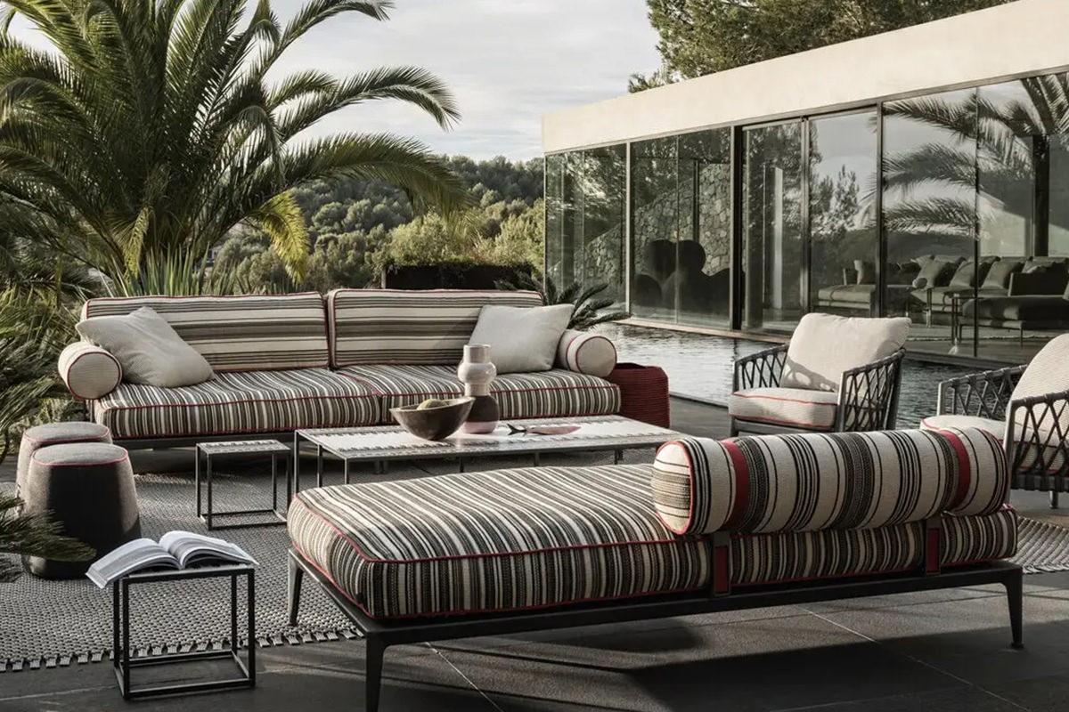 Einladende Outdoor-Lounge von B&B Italia möbliert mit der Ribes Serie mit gestreiften Polstern - Blick auf Pool und Palmen.