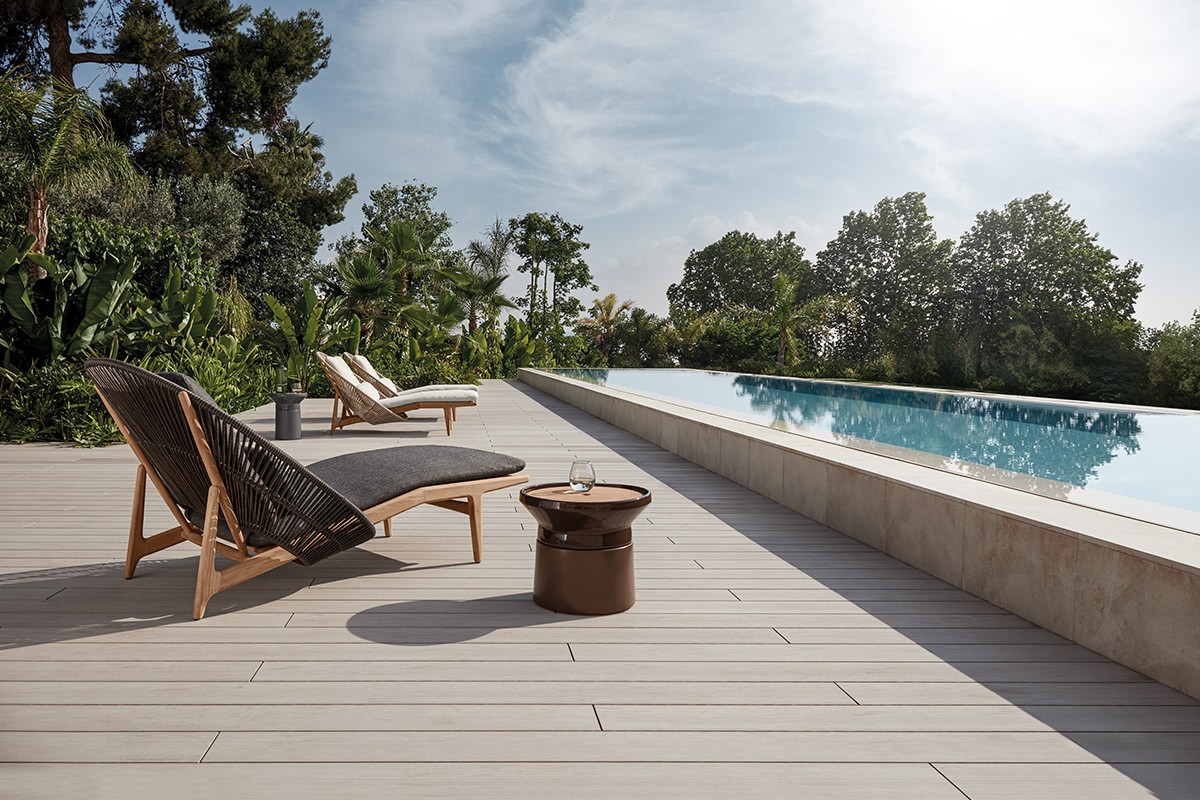 Gloster Bora Sonnenliegen am Pool, umgeben von üppiger Natur und einem klaren Himmel.