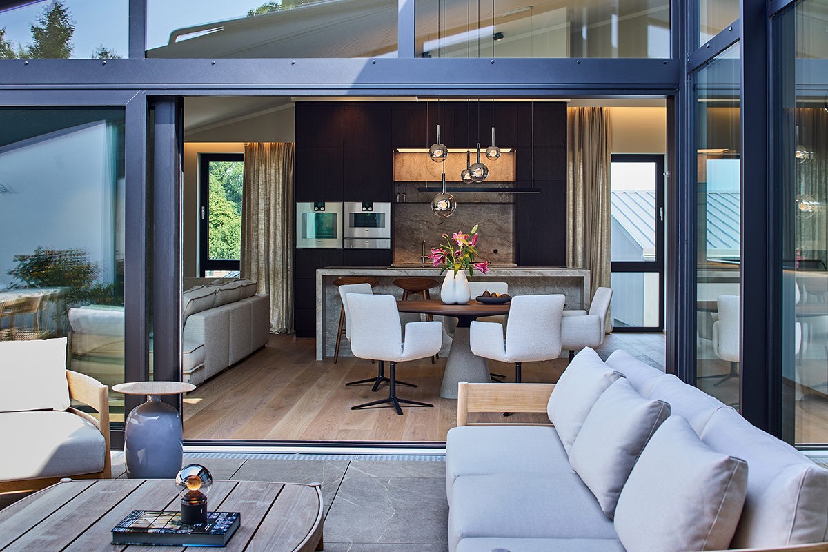 Referenz JB Motors: Patio-Terrasse mit Loungemöbeln und fließendem Übergang zu Essbereich und moderner Küche