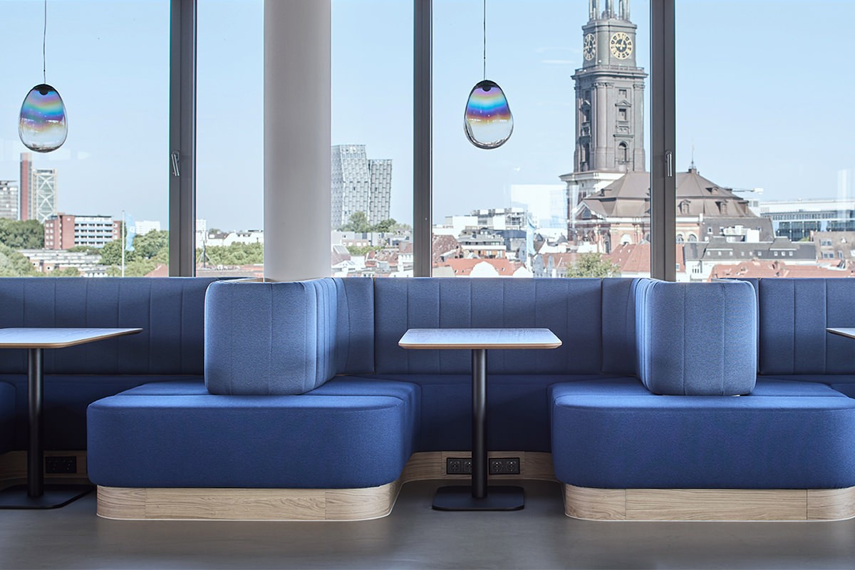Referenz Jebsen & Jessen: Blaue Polster-Sitzkojen an einer Fensterfront mit Blick auf den Hamburger Michel