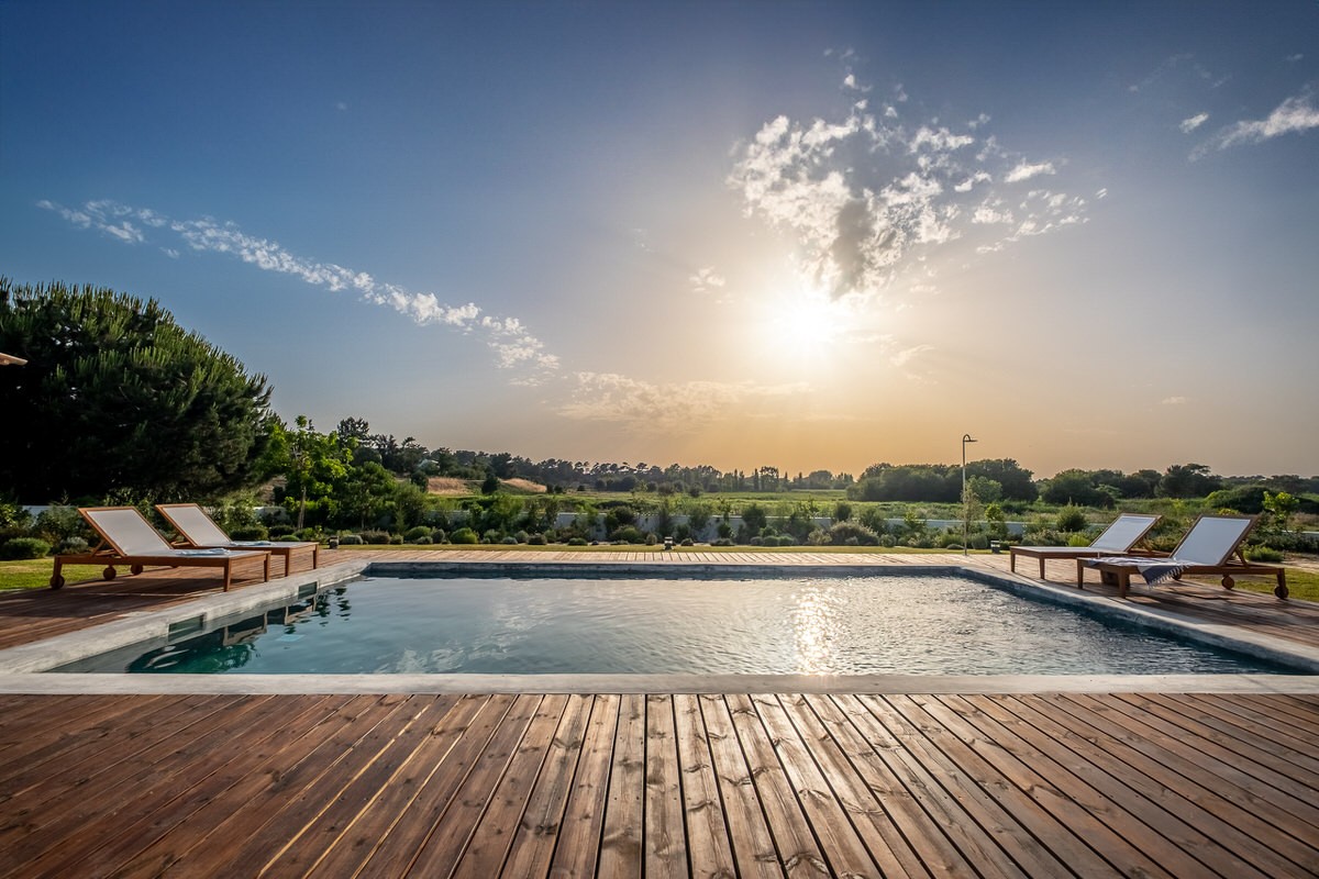 Referenz Ferienhaus in Portugal: Moderner Außenpool mit Holzdeck und Sonnenliegen vor einer weiten Naturlandschaft